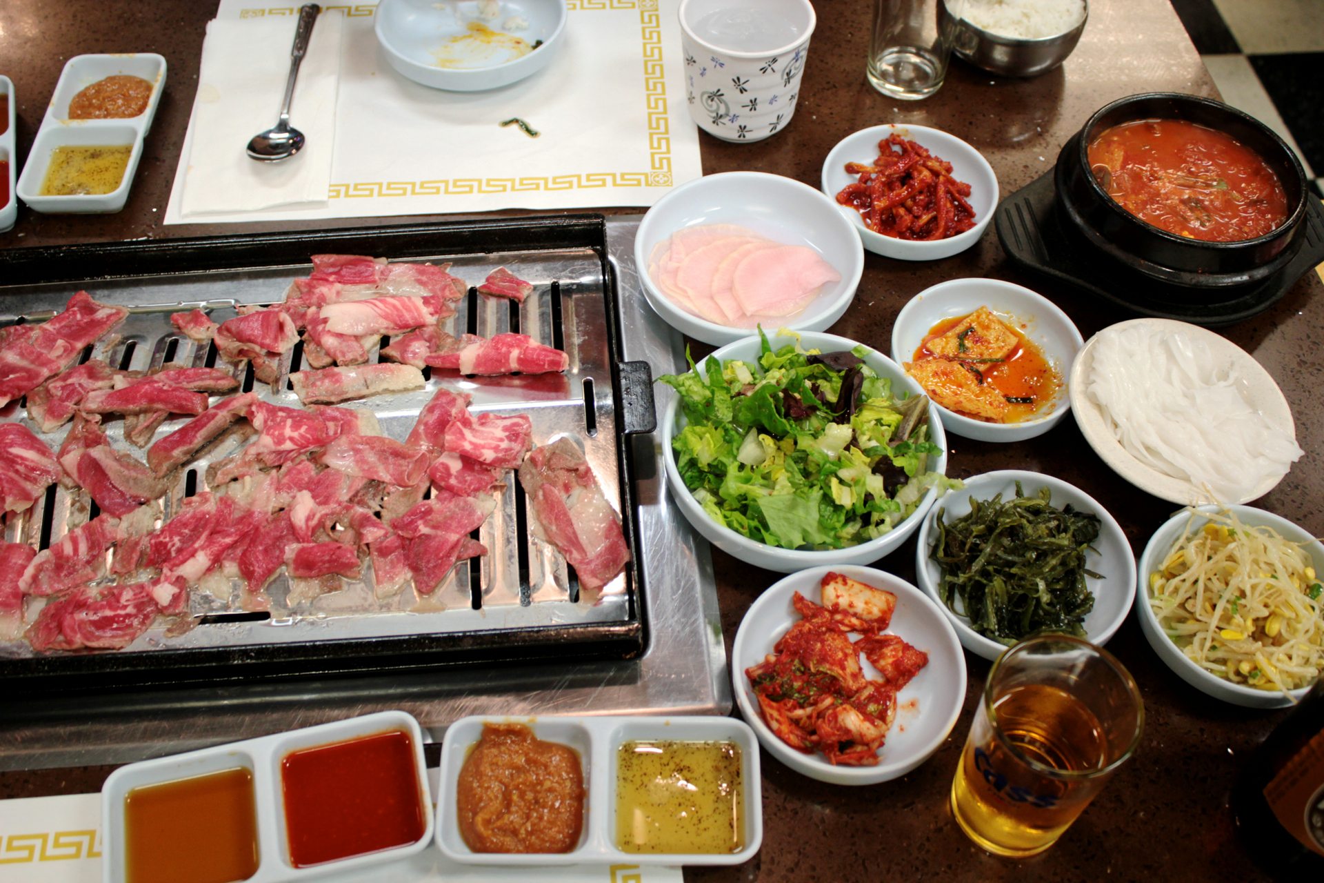 The banchan selections and thinly sliced beef cooking on the grill at To Bang.