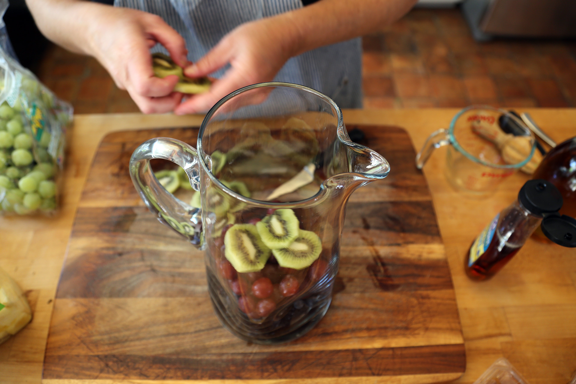 In a large glass pitcher, add layers of fruit in the order of the ingredient list.