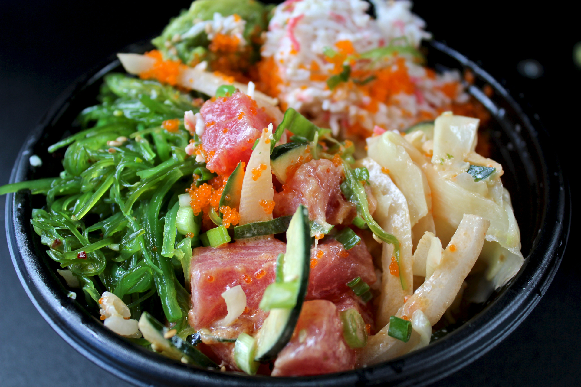 Ahi tuna and salmon with seaweed salad, ginger, cucumbers and green onions at Poki Bowl.