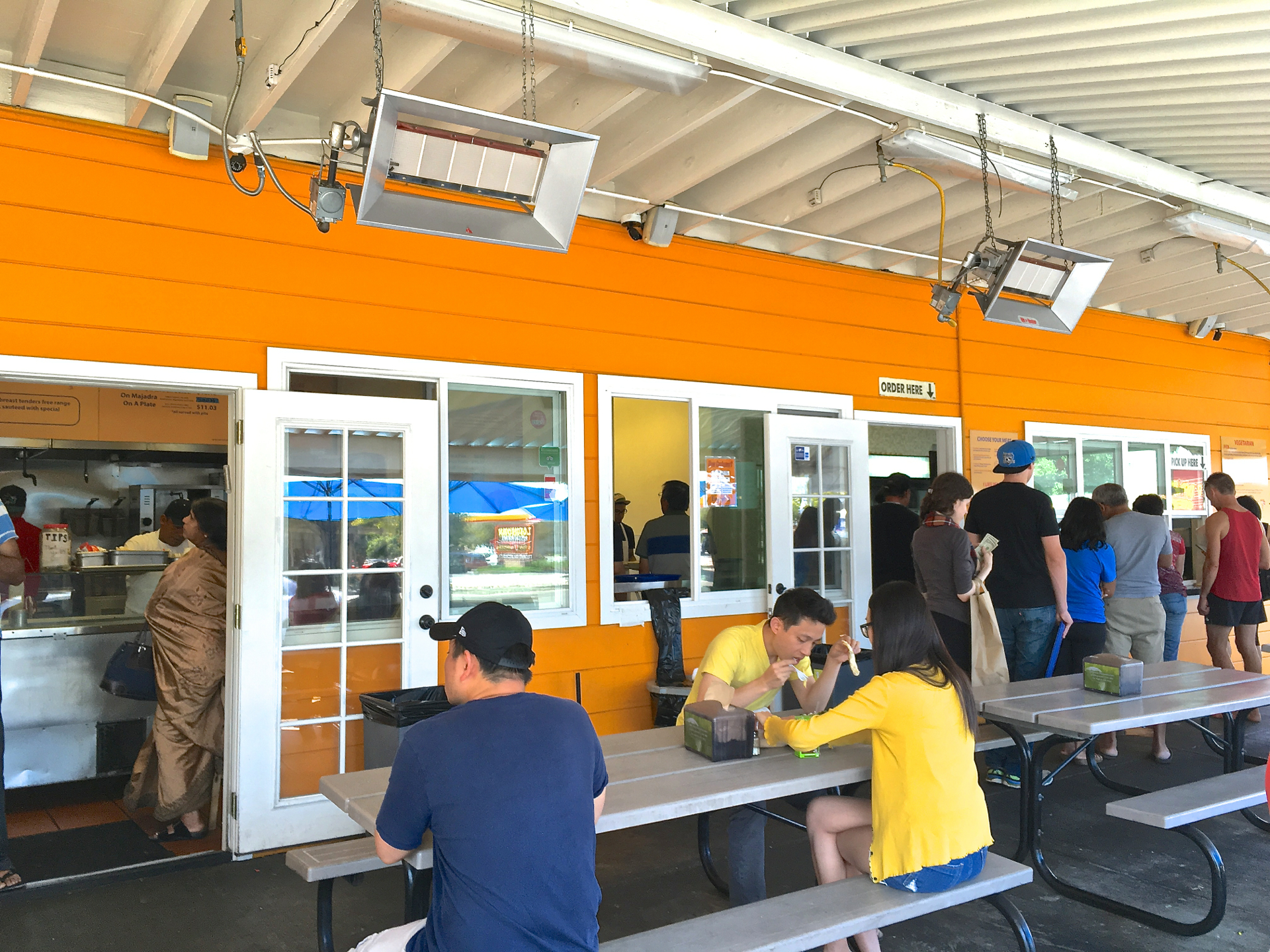 Customers wait on line to pickup their order from the kitchen at Falafel Stop in Sunnyvale.