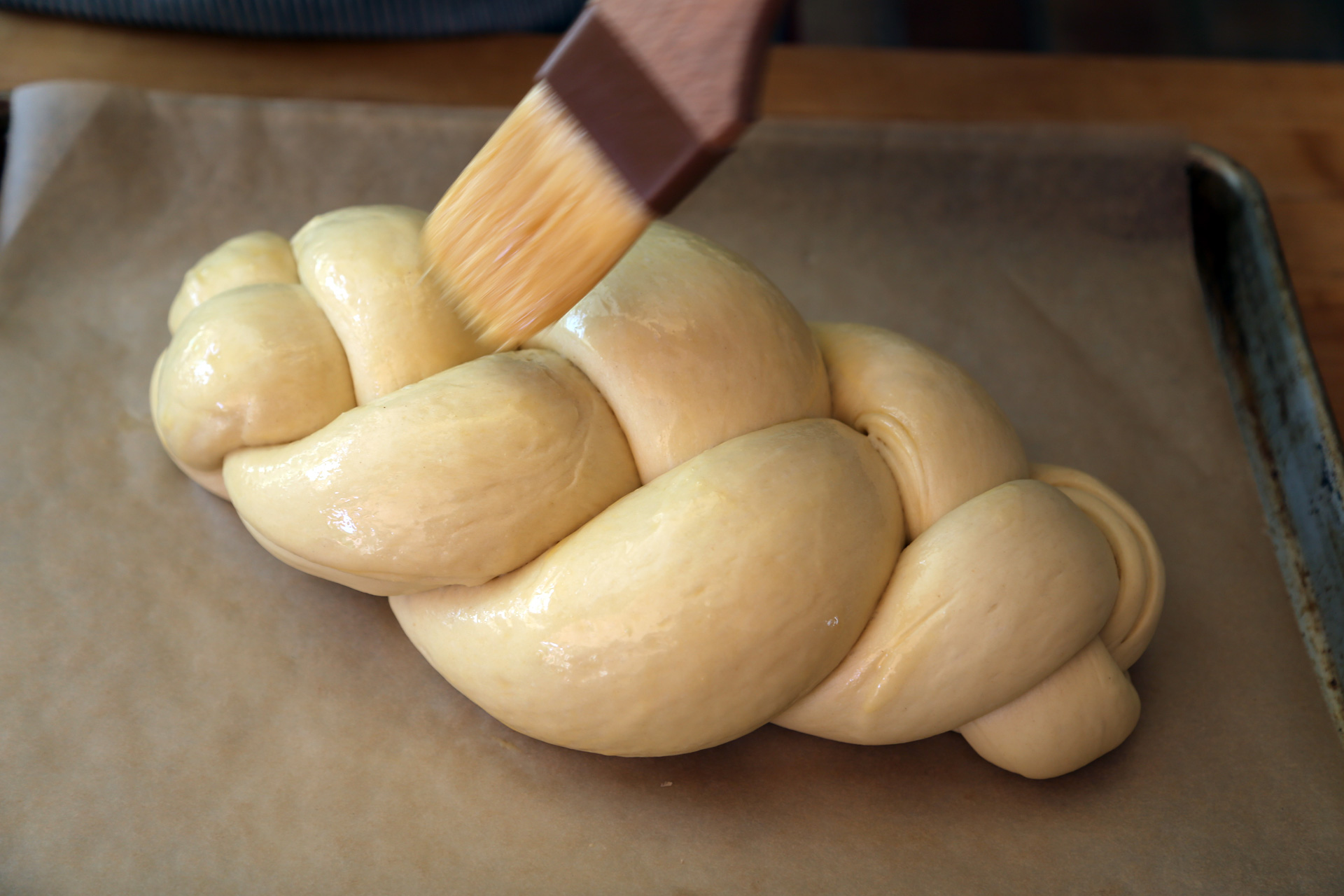 In a small bowl, whisk the remaining egg with 1 teaspoon water until well combined. Using a pastry brush, very gently brush the tops and sides of the challah with the egg wash.