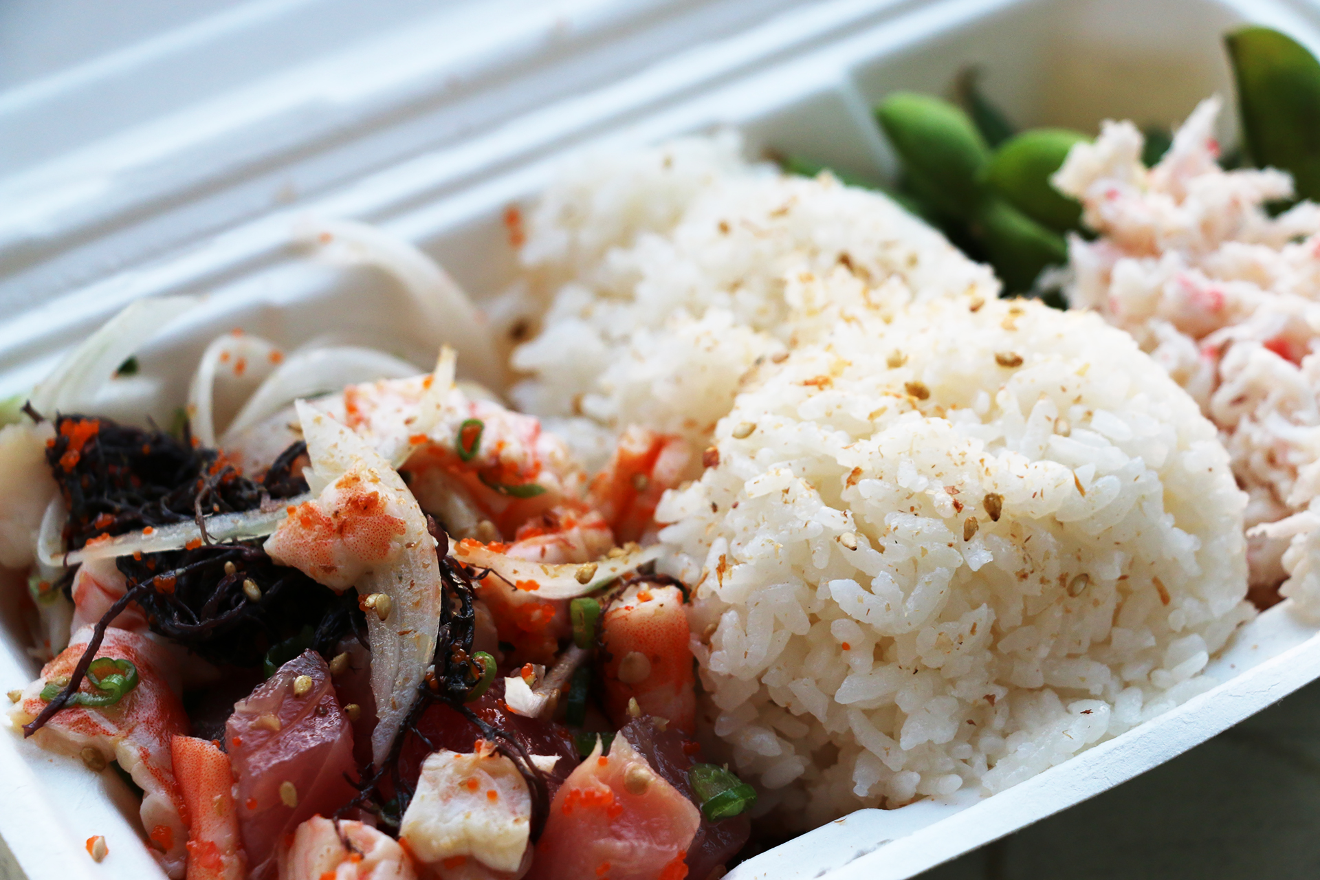A bowl with hamachi, tuna and shrimp on sushi rice.