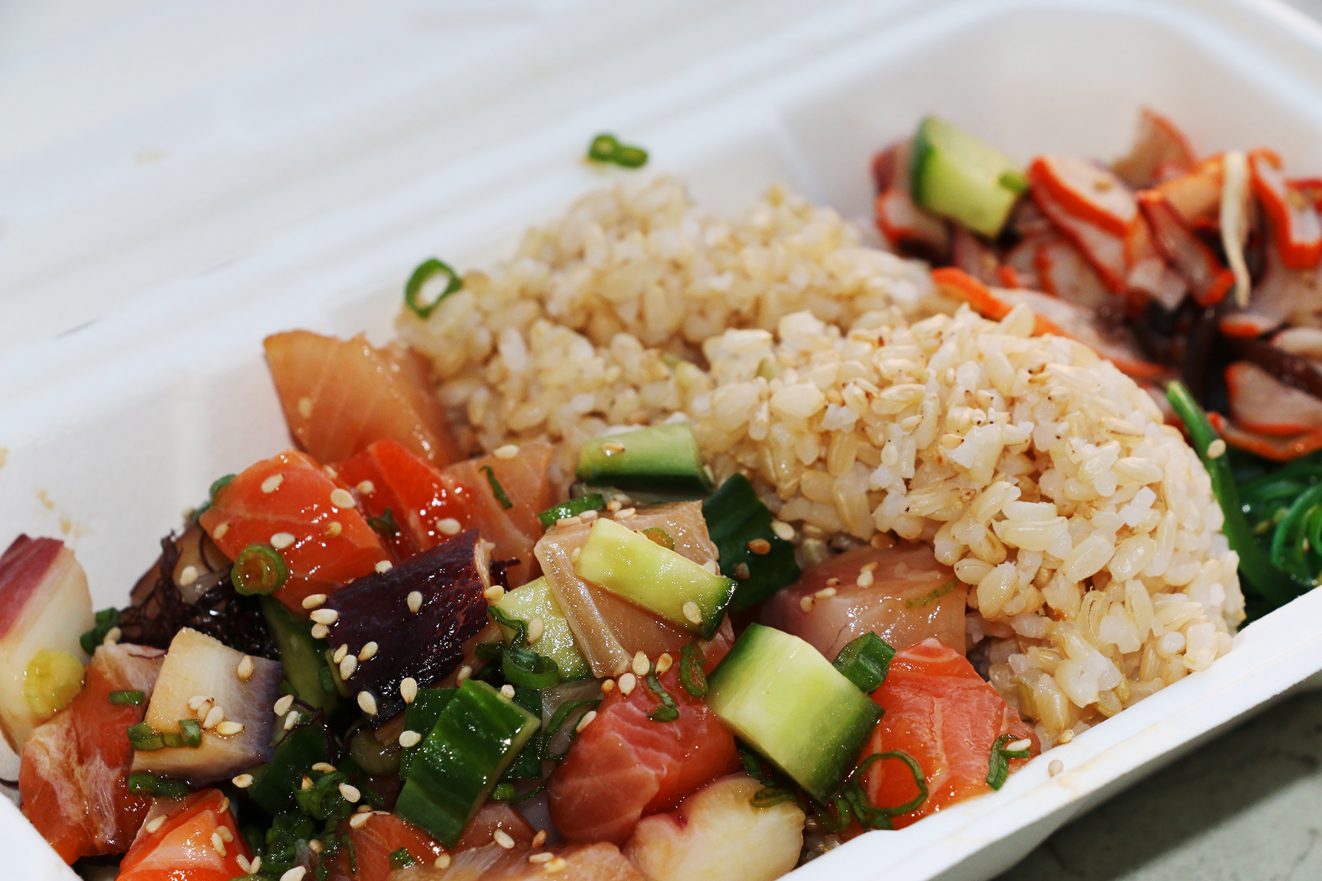 A bowl with salmon, octopus and hamachi on brown rice