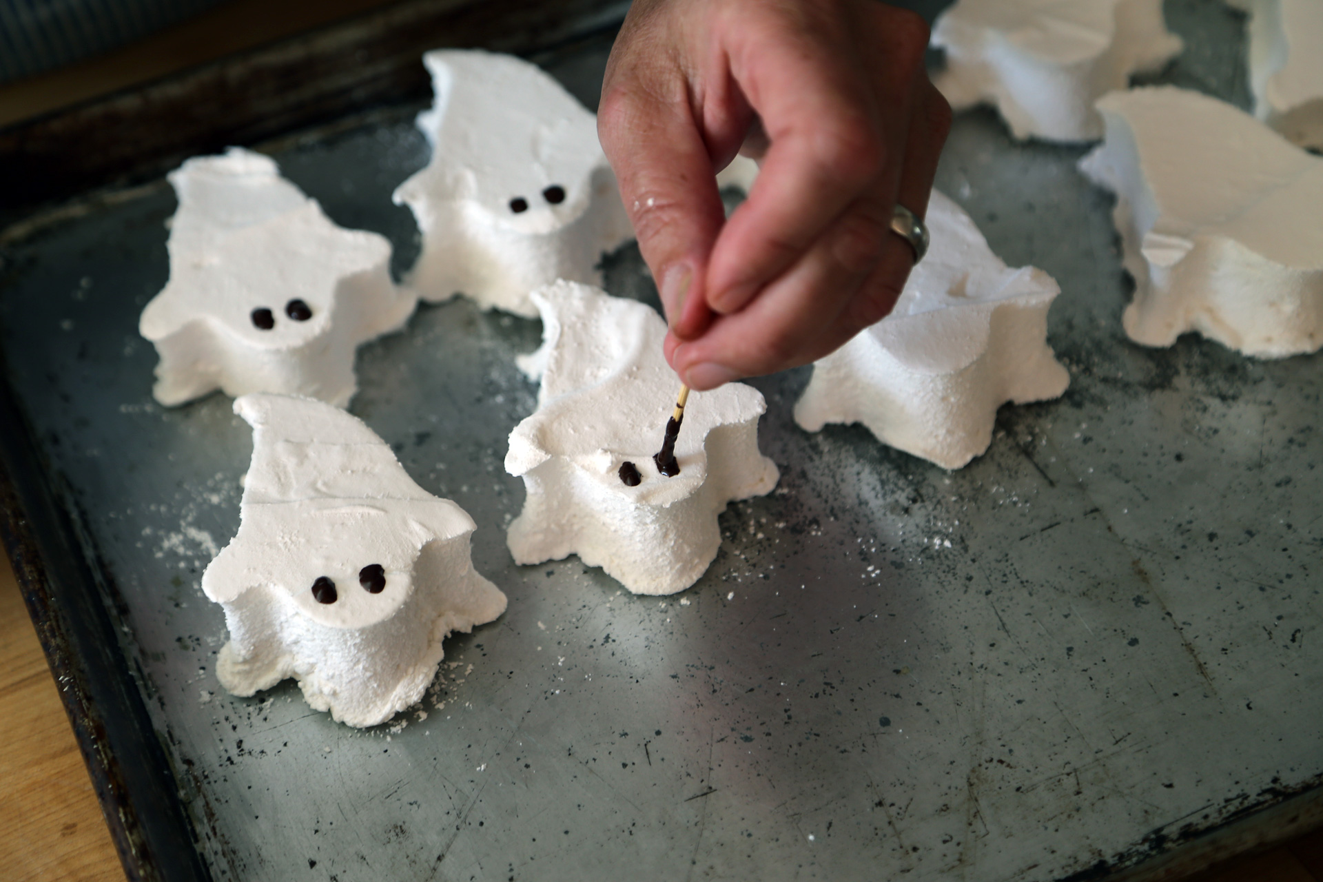 Melt the chocolate chips in a bowl in the microwave at 30-second bursts, stirring each time, until smooth and melted. Use a toothpick to draw spooky eyes and a scary mouth onto the marshmallow ghosts.