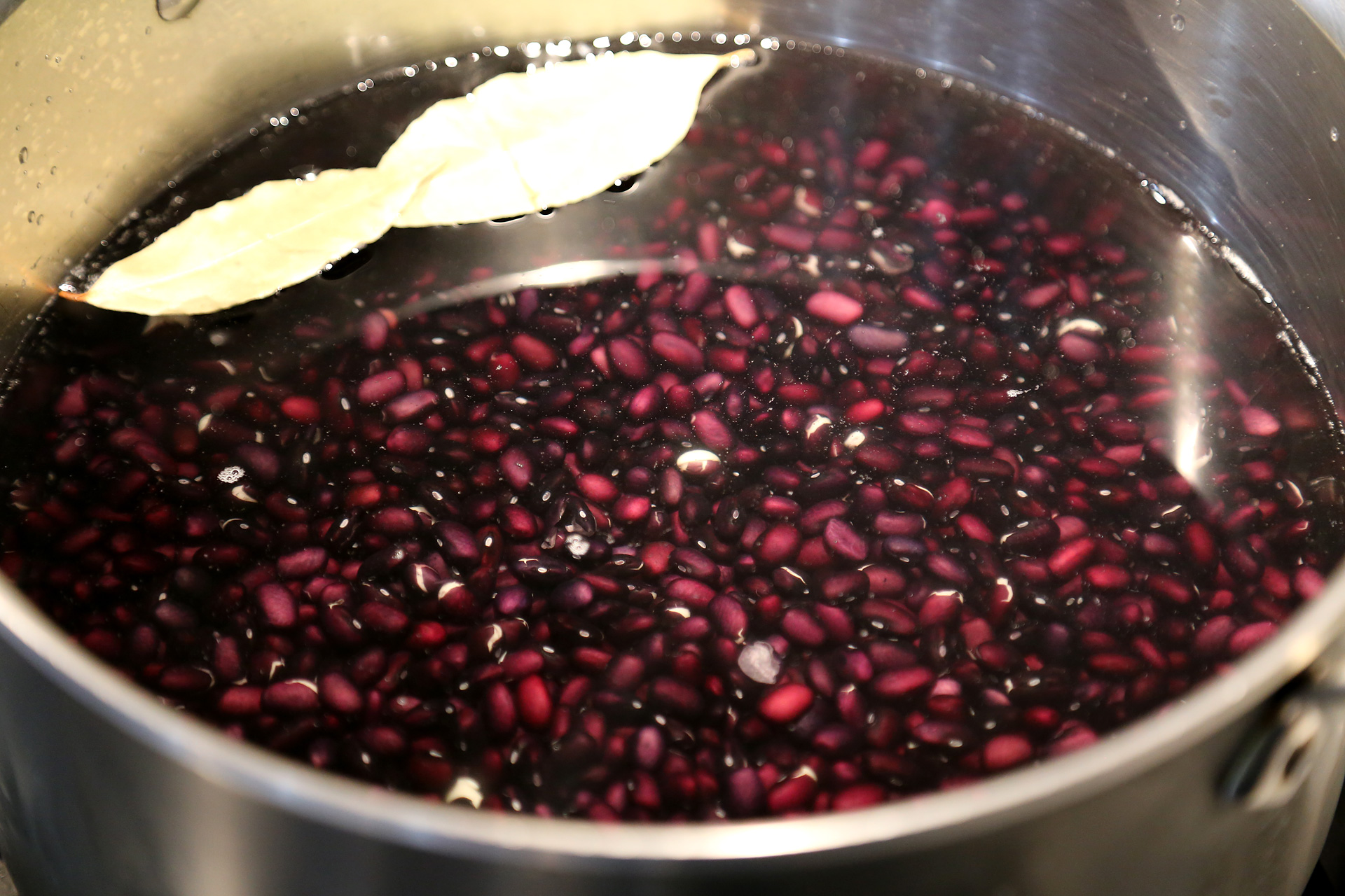 Add the beans, garlic cloves, and bay leaves to a large, heavy saucepan or pot and add cool water to cover by about 1 inch. Bring to a boil over high heat, then cover partially, reduce the heat to low, and simmer, stirring occasionally, until tender.
