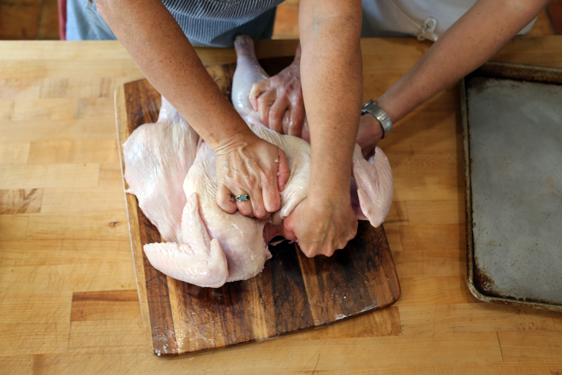 Turn the turkey over so it is breast-side-up and using both your hands and body weight, press down on the turkey to break the breastbone and flatten the bird.