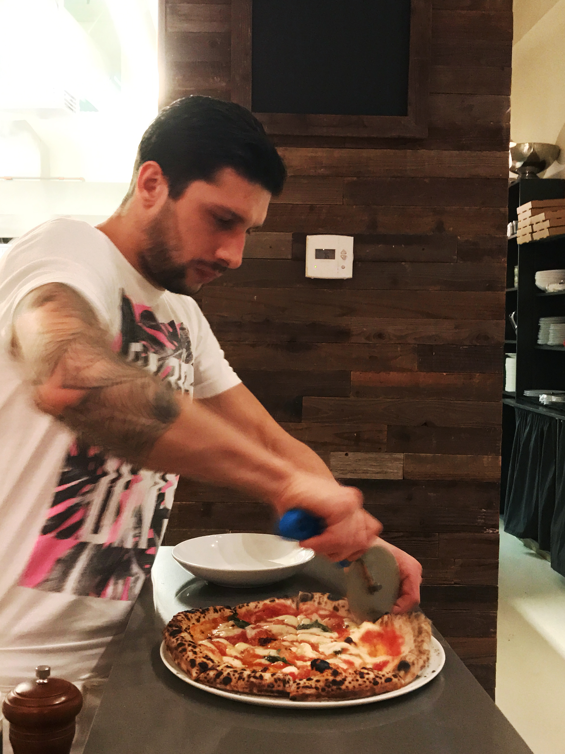 Luciano Passeri cuts into a pizza just before serving.