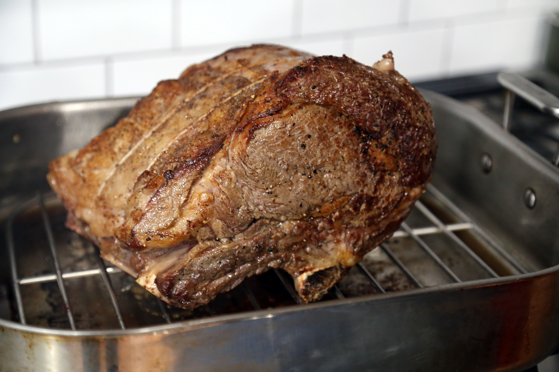 Pull out the roast, add a roasting rack and place the roast bone-side-down on the roasting rack. Transfer to the oven.