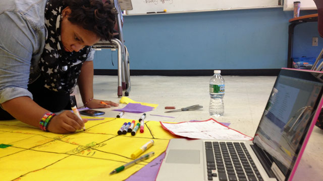 A Science Leadership Academy sophomore puts the finishing touches on a geometry project during her lunch period.