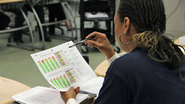 A seventh grade teacher at Clinton Middle School in Los Angeles looks at Early Warning Indicator data during a morning meeting. (Alyson Bryant/Youth Radio)