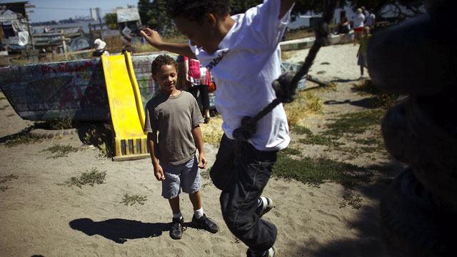 Deion Jefferson, 10, and Samuel Jefferson, 7, take turns climbing and jumping off a stack of old tires at the Berkeley Adventure Playground. David Gilkey/NPR)