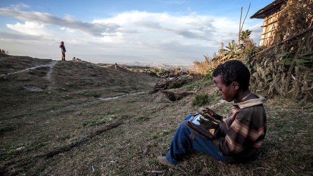 A boy plays with a solar-powered computer tablet on Mount Wenchi, Mirab Shewa Zone of the Oromia Region of Ethiopia. (Courtesy of Tim Freccia/Xprize)
