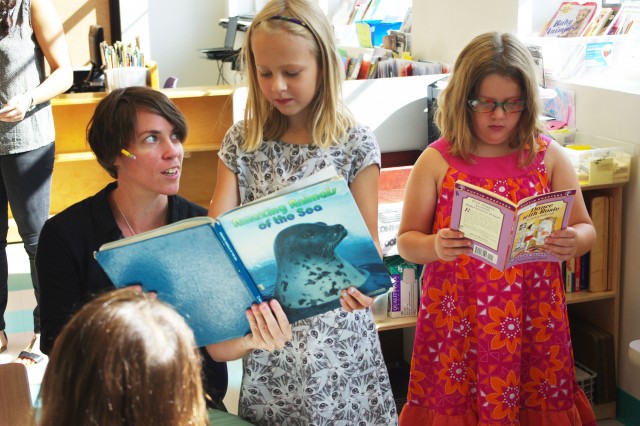 Second-grade teacher Amanda Siepiola reads with Cornelia Blixt and Isabelle Posner-Brown. (Gabrielle Emanuel/NPR)