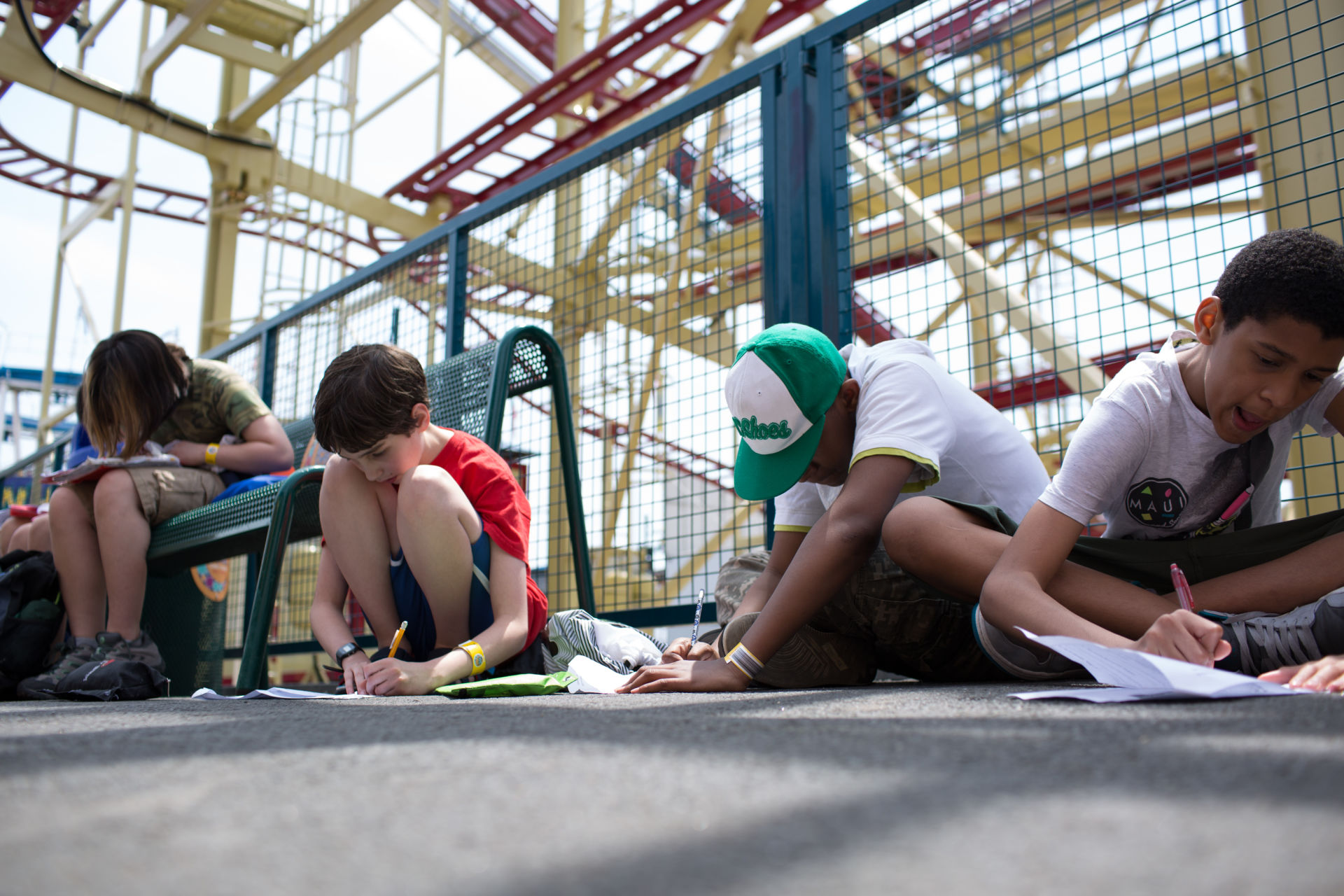 Thea Jones, 12, at left, Etai Kurtzman, 12, Seth Samuel, 12 and Terrell Gantt, 12, fill out game analysis worksheets at Coney Island in Brooklyn, NY May 28, 2015. The group of students from Quest to Learn School took the day trip to Coney Island to analyze user experience on games and rides at Luna Park as part of  their late-spring school curriculum. 