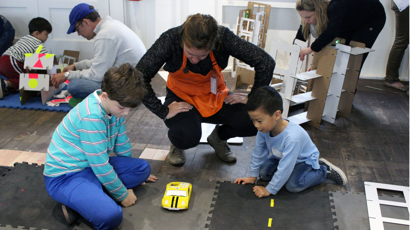 A facilitator helps kids figure out how to program one of the cars in the Fab Lab.