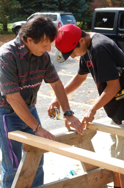John Gizzi is helping Kirwin Parsons to build a picnic table for the school.