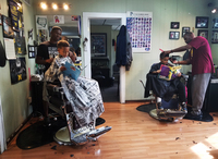 Joziah and Jozef read to their barbers at the Fuller Cut in Ypsilanti, Mich. As part of the barbershop's literacy program, children get $2 off their cut for reading a book to their barber.