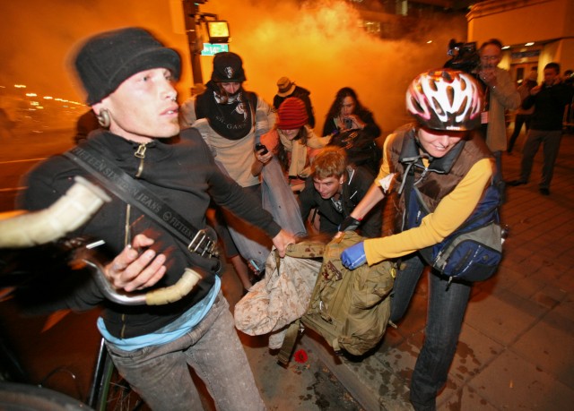 Occupy Oakland protesters carry injured former Marine Scott Olsen after he was struck in the head with a police projectile during unrest in October 2011. Olsen has a lawsuit pending against the city, which settled a suit with a second veteran, Kayvan Sabeghi, for $645,000. (Kimihiro Hoshino/AFP/Getty Images)