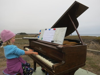Six-year-old Penelope Keep performs at Francis Beach in Half Moon Bay on one of twelve old pianos that artist Mauro Fortissimo hauled out to the beaches of San Mateo County. (Francesca Segrѐ/ KQED)