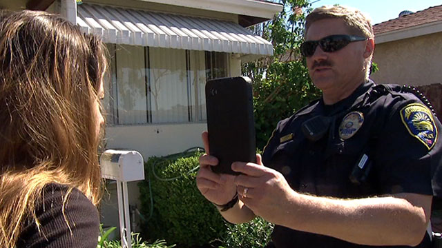 Officer Rob Halverson, with the Chula Vista Police Department in California, uses a Samsung Galaxy tablet to identify a woman as part of a pilot program in San Diego County, testing facial recognition software. (Roque Hernandez/Univision)