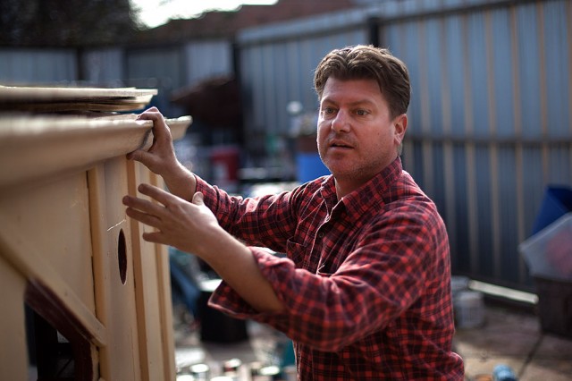 Kloehn fits a wooden gutter on the exterior of a tiny house he refers to as the 'Uni-bomber Shack.' (Mark Andrew Boyer/KQED)