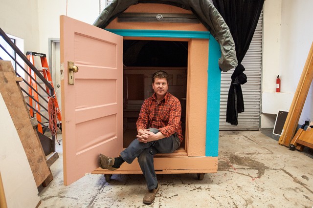 Artist and designer Gregory Kloehn sits in the doorway of his latest tiny house, which he calls the Chuckwagon. (Mark Andrew Boyer/KQED)