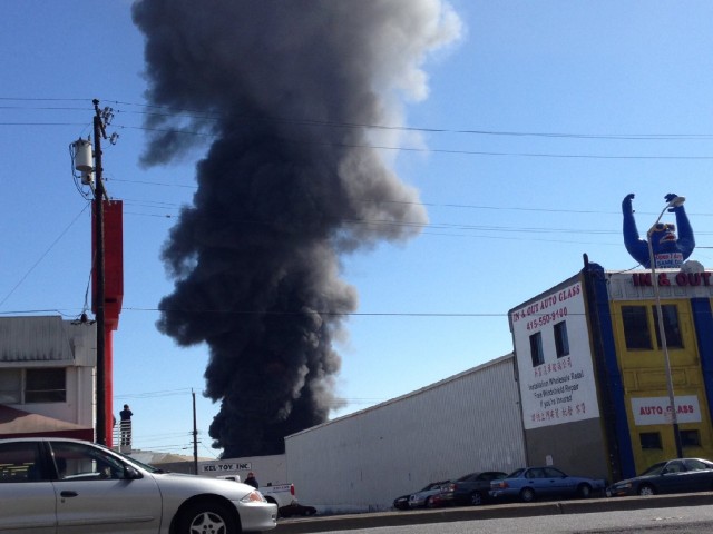A fire in a taxicab garage in San Francisco's Bayview neighborhood sent an attention-getting plume of black smoke into the air at midday Monday. (Francesca Segre/KQED)