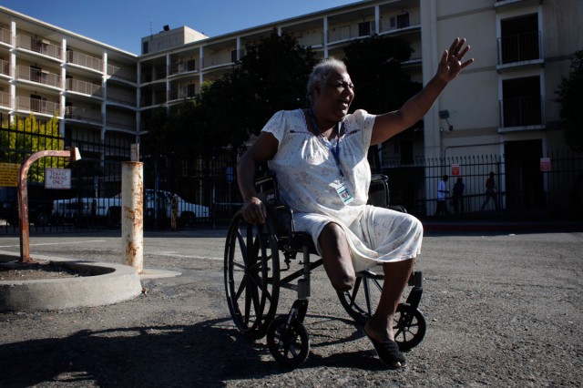 Rhonda Marshall, 58, waves to visitors outside the Hacienda public housing complex. She’s been living on the high-rise’s first floor for years and has watched the building deteriorate. She says sees cracks in the walls running from the sixth floor to the ground and smells mold in the hallways and stairwells. (Lacy Atkins/San Francisco Chronicle)