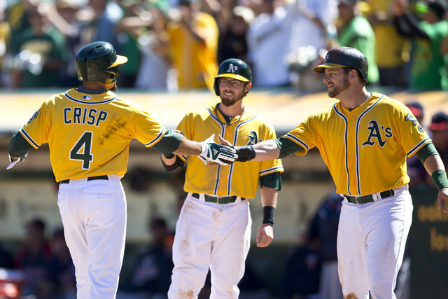 Coco Crisp is congratulated by Eric Sogard, center, and Stephen Vogt after hitting a three-run homer in the Oakland A's division-clinching win against the Minnesota Twins last September. (Jason O. Watson/Getty Images)