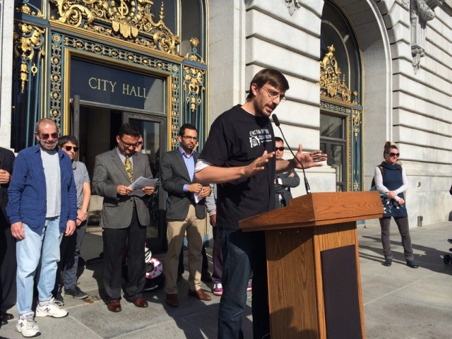Tenants call on city officials to boost funding for eviction defense. At podium: Tyler McMillan, executive director of the Eviction Defense Collaborative. (Bryan Goebel/KQED)