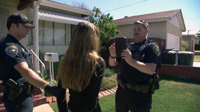 Officer Rob Halverson of the Chula Vista police verifies the identity of a woman just arrest for possession of narcotics with facial recognition software. (Center for Investigative Reporting)