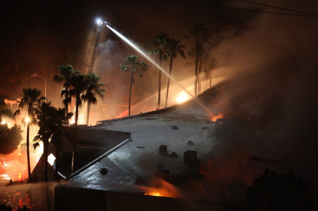 Firefighters spray water on burning building in the San Diego County town of Carlsbad. (David McNew/Getty Images)