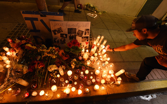 A student lights a candle at a makeshift memorial outside the IV Deli Mart where one of the victims of a killing spree was shot and killed near the University of California, Santa Barbara campus during a candlelight vigil for those affected by the tragedy in Isla Vista on May 24, 2014 in Santa Barbara, California. Elliot Rodger, the British-born son of a Hollywood film-maker stabbed three men to death in his apartment before killing three more people in a shooting spree in Santa Barbara, California, police said. AFP PHOTO/ROBYN BECK (Photo credit should read ROBYN BECK/AFP/Getty Images)
