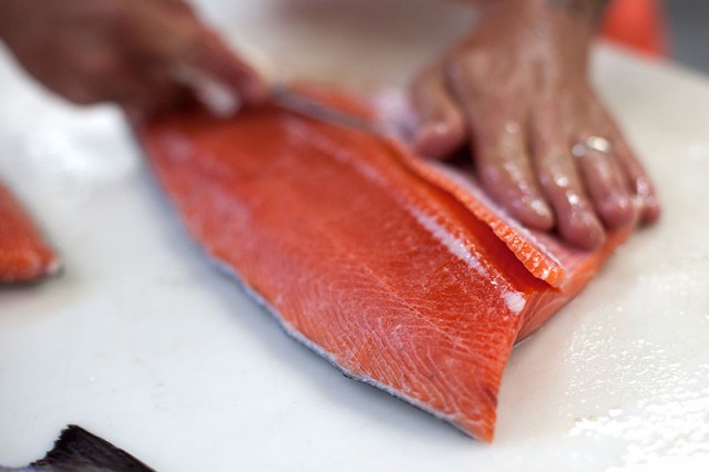 Kenny Belov, co-owner of TwoXSea, cuts a piece of salmon (Mark Andrew Boyer/KQED)