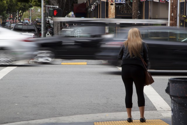 A pedestrian waits to cross South Van Ness Avenue at 24th Street in the Mission. (Mark Andrew Boyer/KQED)