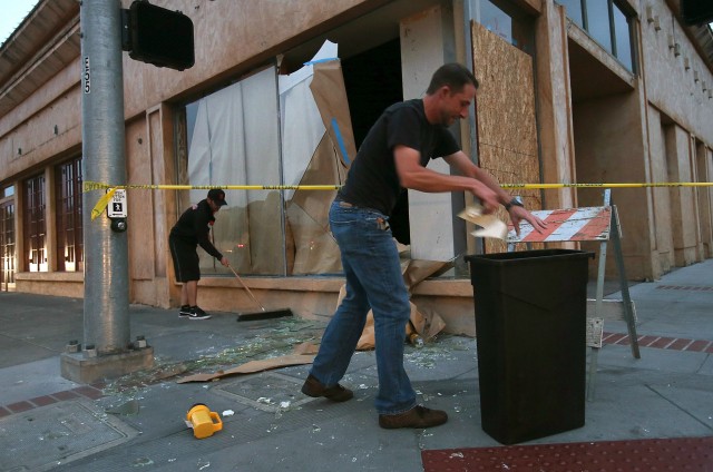 Workers clean up broken glass in front of a damaged building. (Justin Sullivan/Getty Images)