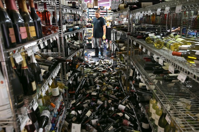 A worker looks at a pile of wine bottles that were thrown from the shelves at Van's Liquors. (Justin Sullivan/Getty Images)