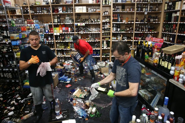  Workers clean up piles of bottles that were thrown from the shelves at Van's Liquors. (Justin Sullivan/Getty Images)