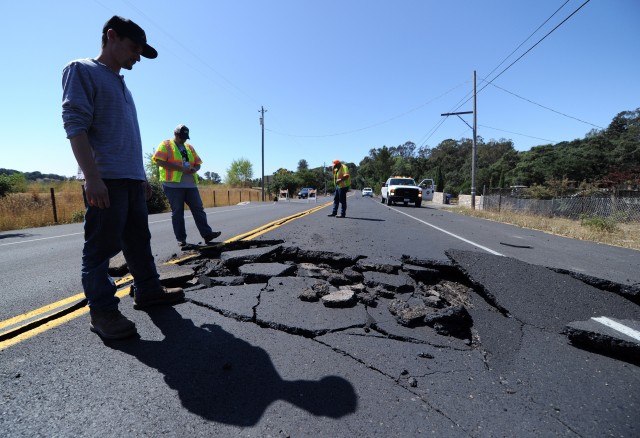 Nicholas George looks under a buckled highway just outside of Napa, California. (Josh Edelson/AFP/Getty Images)