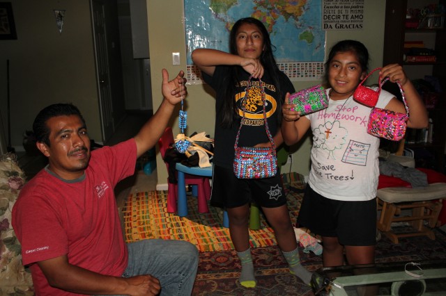 Gerardo Mendoza and daughters Esther (12) and Kelly (10) show items Mendoza made for them while being held in ICE detention for 26 months--purses and tiny shoes out of recycled Ramen noodle rappers. Mendoza's wife and three children didn't see him in person for more than two years. Though he was released a few months ago, he's still awaiting a final decision in his quest for US status.