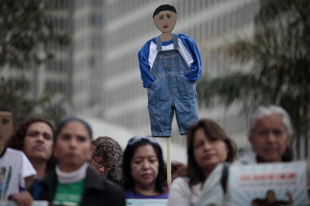 A protester holds up a cardboard cutout of a child before a march protesting deportation of minors and families. (James Tensuan/KQED)