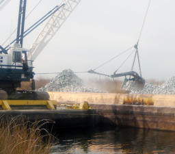 A crane barge takes a load off a rock barge as part of a levee maintenance operation in the Delta. (Lisa Morehouse/KQED)