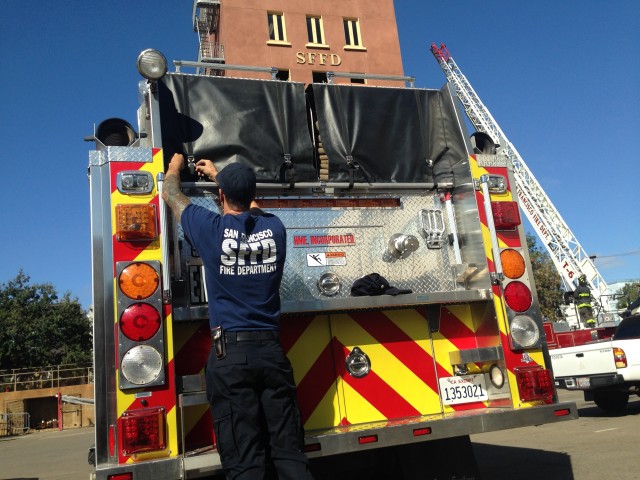 A member of the San Francisco Fire Department prepares an engine that's heading to the King Fire, northeast of Placerville. (Isabel Angell/KQED)
