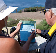 Sheila Parker (L) shows a volunteer the day's whale census log sheet. This year's gray whale count at Point Vicente is the highest in 16 years. (Marcus Teply/KQED)