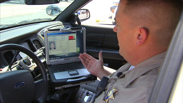 A Los Angeles County sheriff’s deputy demonstrates a mobile fingerprint reader. Officials say biometric information would be retained indefinitely. (KNBC-TV)