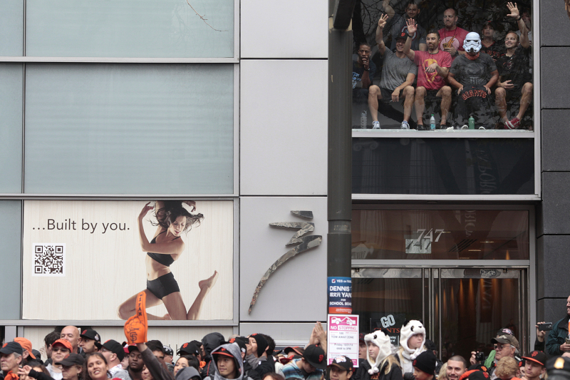 Fans watch from Market St. as the Giants Parade goes underway in San Francisco. (James Tensuan/KQED)