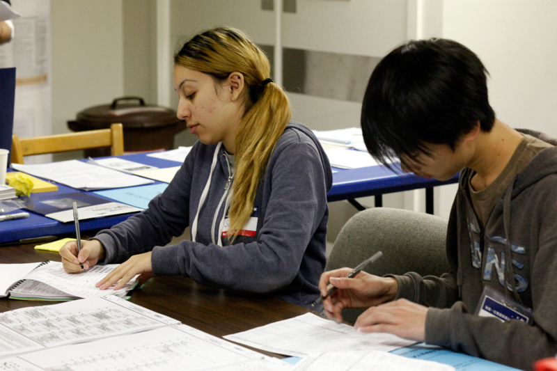 Samantha Padilla, 17, of Sacred Heart Cathedral Preparatory School and Jerry Gong, 17, of Galileo High School volunteer as poll workers at the Dolores Park Church polling place. (Katie Brigham/KQED)