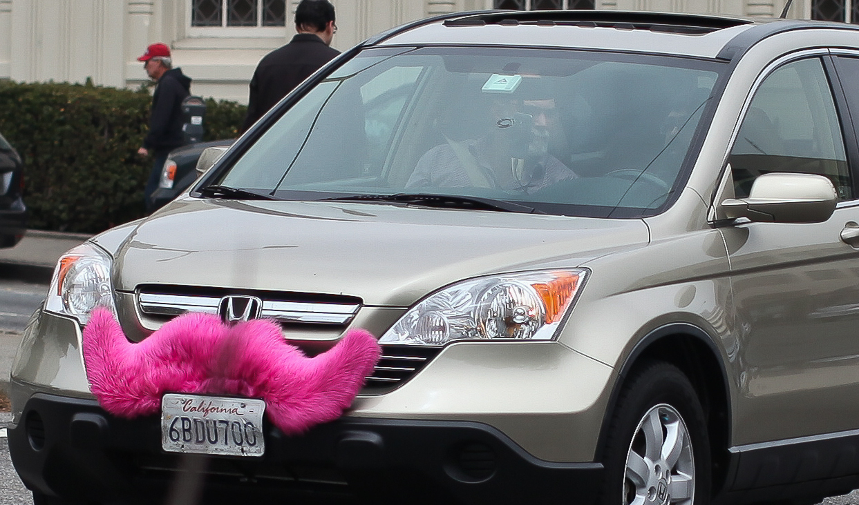 A Lyft car, sporting the pink mustache .