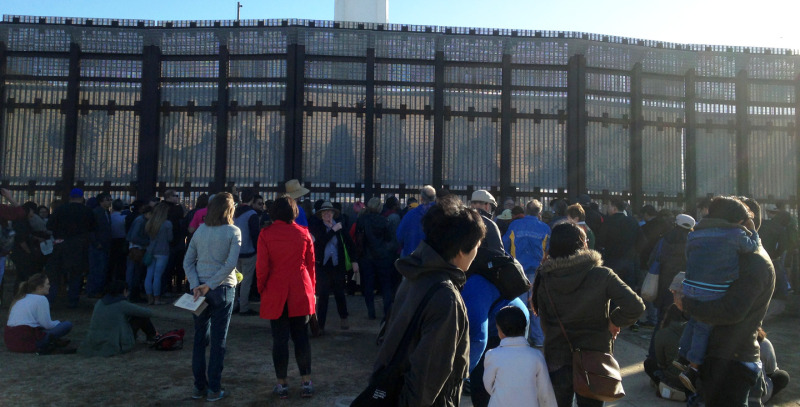 People gather at the foot of the U.S.-Mexico border fence at the annual La Posada Sin Fronteras.
