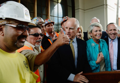 Gov. Jerry Brown stands next to construction workers and elected officials after signing legislation authorizing initial construction of California's $68 billion high-speed rail line on July 18, 2012 in Los Angeles. (Kevork Djansezian/Getty Images)